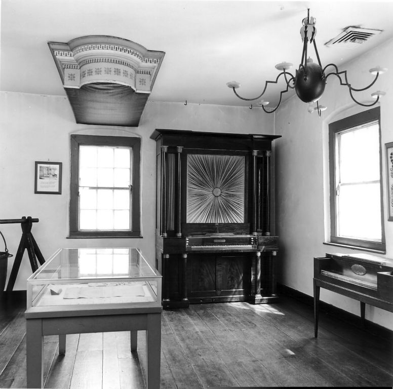 The organ on display in the Boys' School as part of the Wachovia Historical Society collection, early 1950's. Note the cornice of the 1800 David Tanneberg Home Moravian church organ attached to the ceiling. (Photo courtesy of Old Salem, Inc.)
